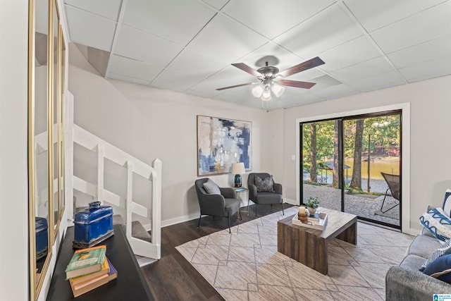 living room featuring hardwood / wood-style floors, ceiling fan, and a drop ceiling