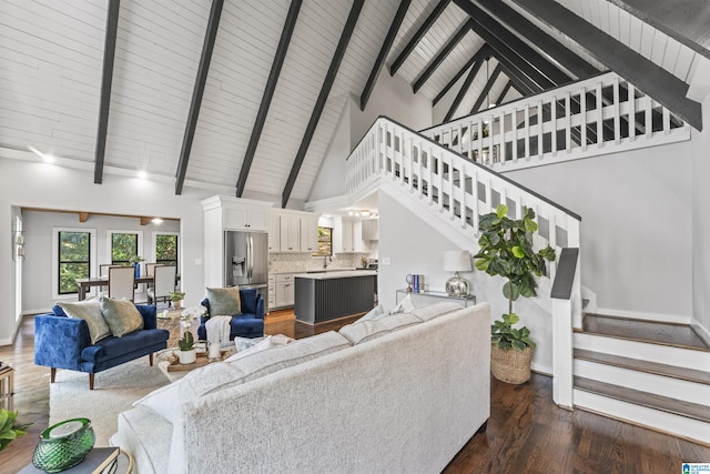 living area with dark wood-style flooring, high vaulted ceiling, stairway, and beamed ceiling