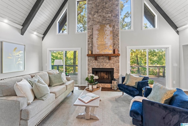 living room with high vaulted ceiling, hardwood / wood-style floors, a stone fireplace, wooden ceiling, and beam ceiling