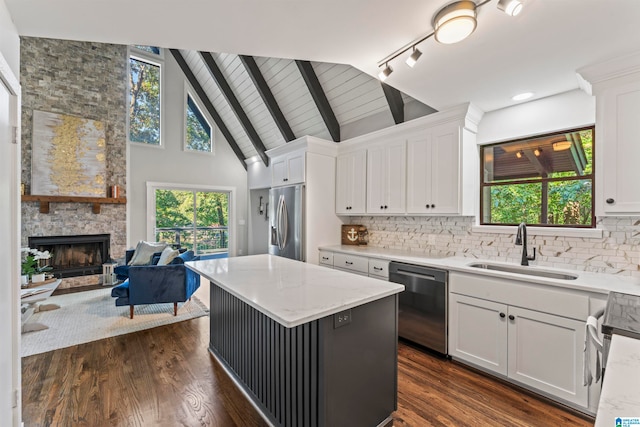 kitchen featuring a kitchen island, a fireplace, appliances with stainless steel finishes, sink, and white cabinetry