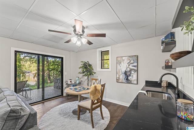 dining space with dark wood finished floors, baseboards, ceiling fan, and a drop ceiling