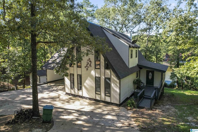 back of property with a shingled roof and concrete driveway