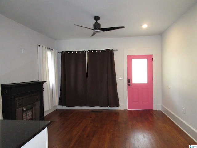 foyer entrance featuring a fireplace, dark wood-type flooring, and ceiling fan