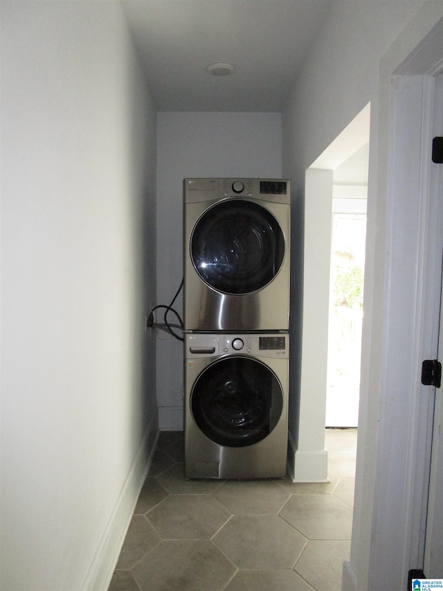 clothes washing area with tile patterned flooring and stacked washer / dryer