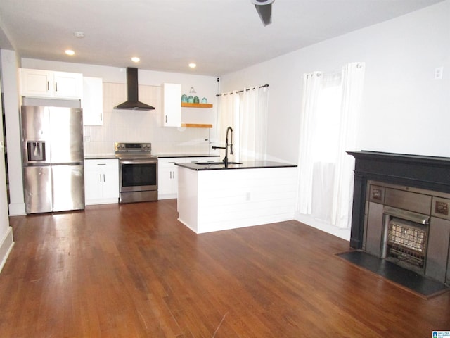 kitchen featuring sink, dark wood-type flooring, appliances with stainless steel finishes, white cabinets, and wall chimney range hood