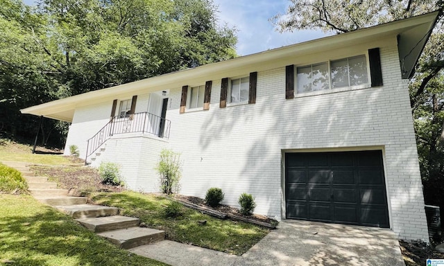 view of front of property with a garage, concrete driveway, brick siding, and stairs