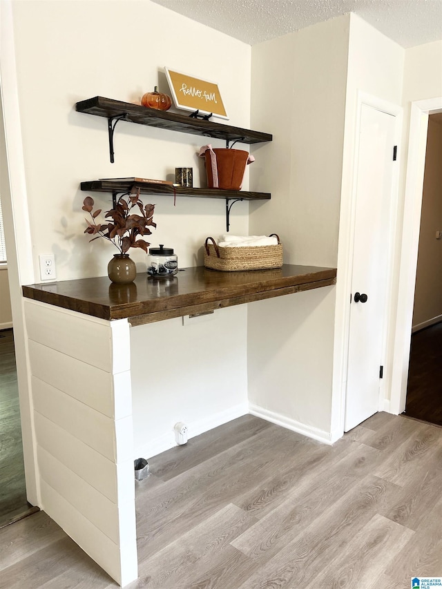 bar featuring a textured ceiling, baseboards, and wood finished floors