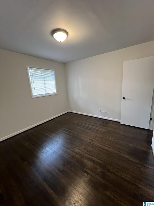 empty room featuring dark wood-style floors and baseboards