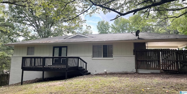 view of front of property featuring fence, a deck, french doors, and brick siding