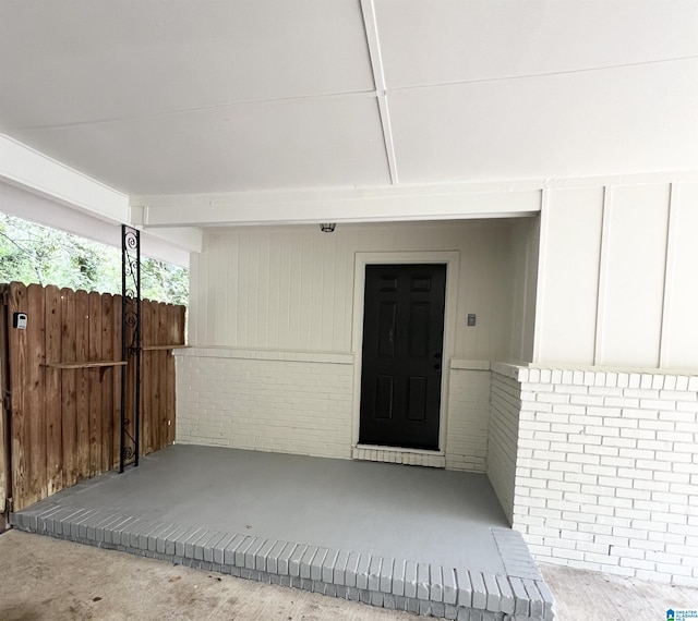 doorway to property with brick siding and fence