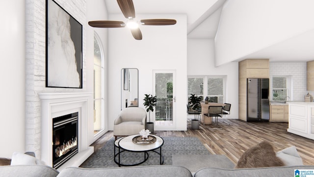 living room with a fireplace, wood-type flooring, ceiling fan, and a high ceiling