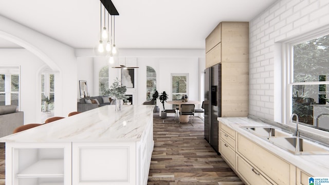 kitchen featuring stainless steel fridge, sink, cream cabinetry, a center island, and dark hardwood / wood-style floors