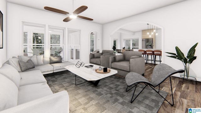 living room featuring ceiling fan with notable chandelier, a healthy amount of sunlight, and dark hardwood / wood-style flooring