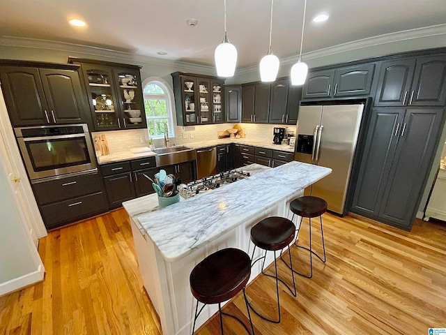 kitchen featuring crown molding, a center island, appliances with stainless steel finishes, and light hardwood / wood-style floors