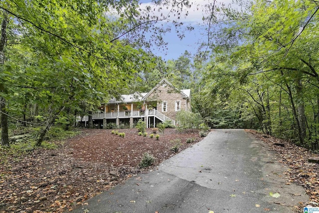 view of front of property with a forest view, aphalt driveway, and stairway