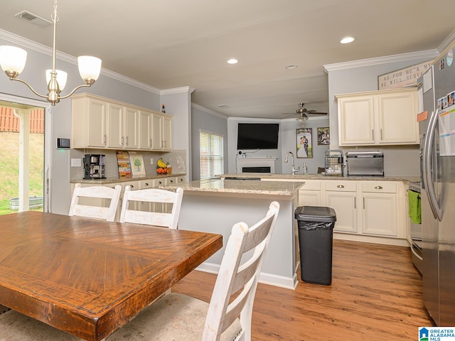 dining room with ceiling fan with notable chandelier, ornamental molding, light hardwood / wood-style flooring, and sink