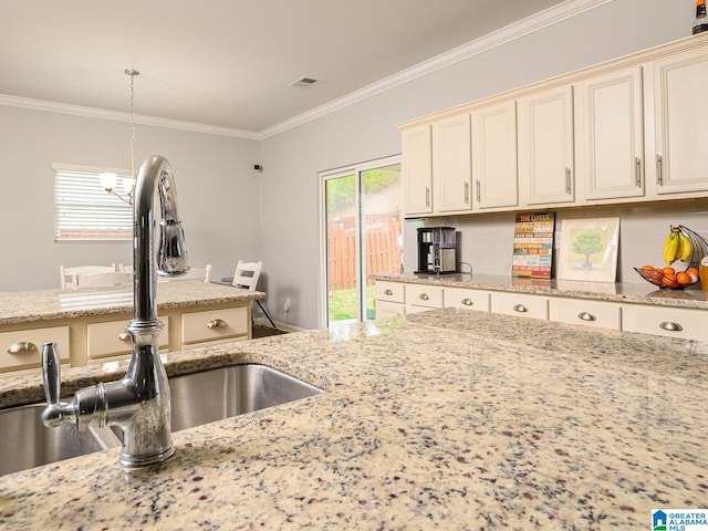 kitchen featuring cream cabinetry, light stone countertops, and a healthy amount of sunlight