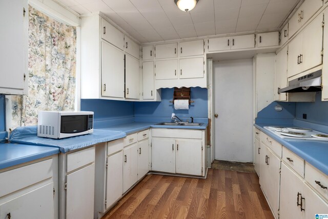 kitchen with white appliances, dark hardwood / wood-style flooring, sink, and white cabinets