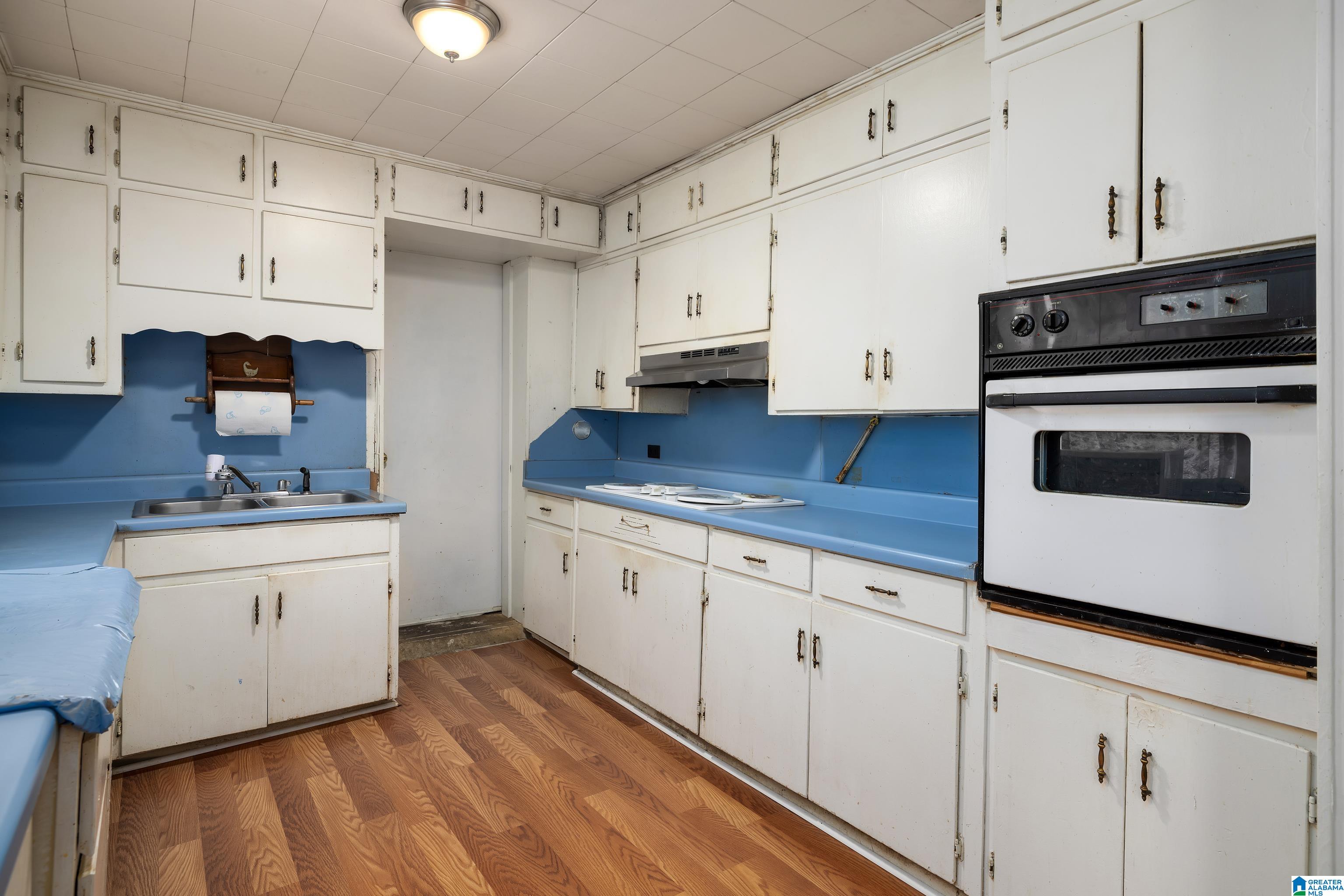 kitchen with white cabinets, white appliances, hardwood / wood-style flooring, and sink