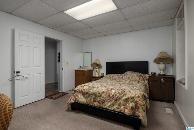 bedroom featuring a paneled ceiling and light colored carpet