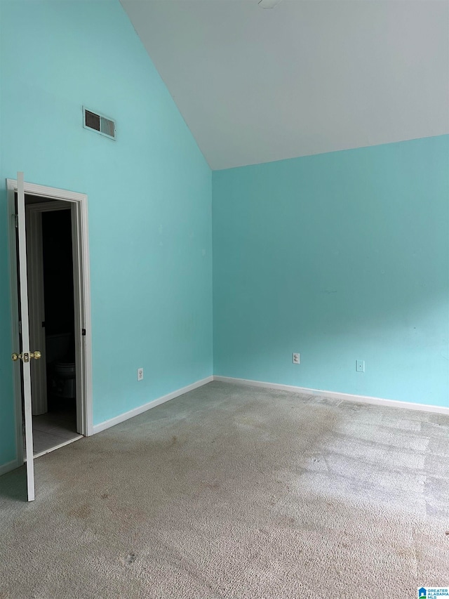 empty room with high vaulted ceiling and carpet floors