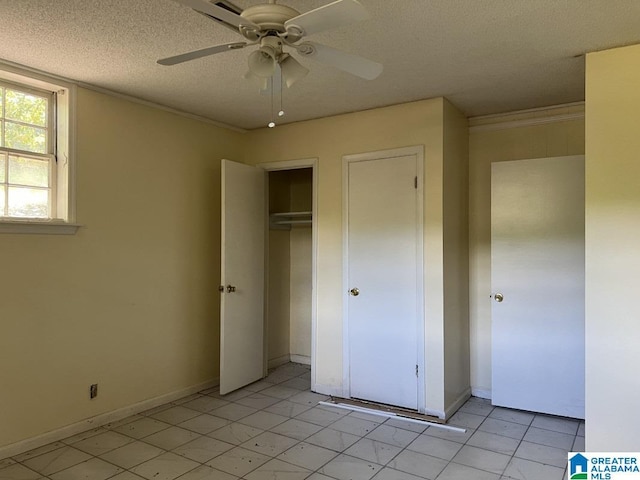 unfurnished bedroom with a textured ceiling, baseboards, a ceiling fan, and crown molding