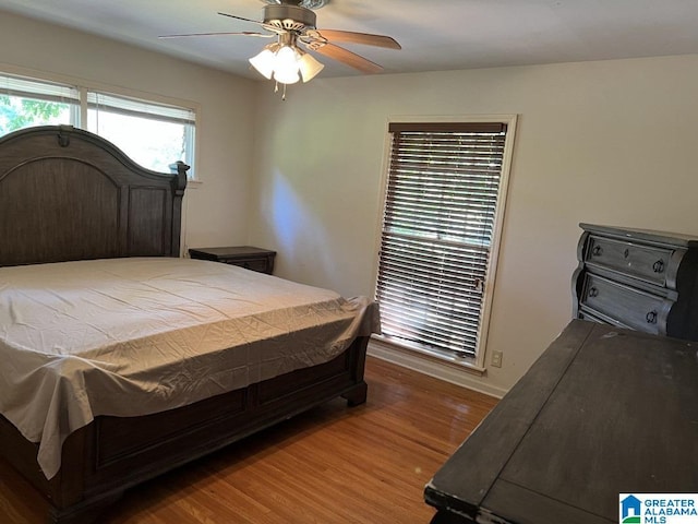 bedroom with ceiling fan, wood finished floors, and baseboards