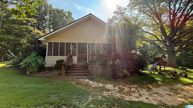 view of front of home featuring a playground, a front lawn, and a sunroom