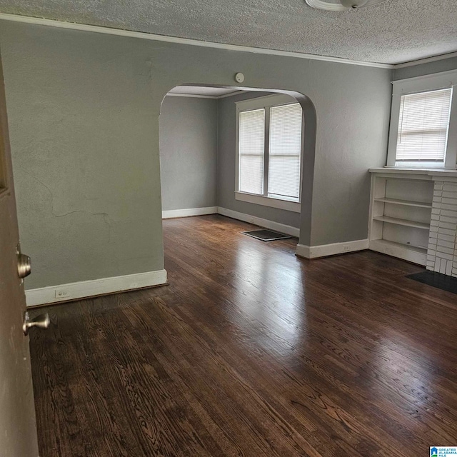 empty room with a wealth of natural light, ornamental molding, and dark hardwood / wood-style flooring