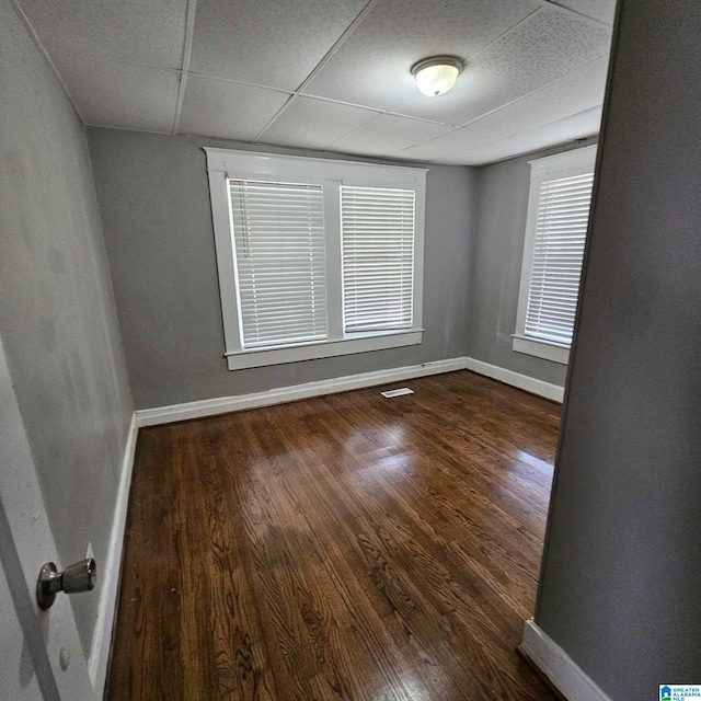 empty room with a paneled ceiling and dark hardwood / wood-style floors