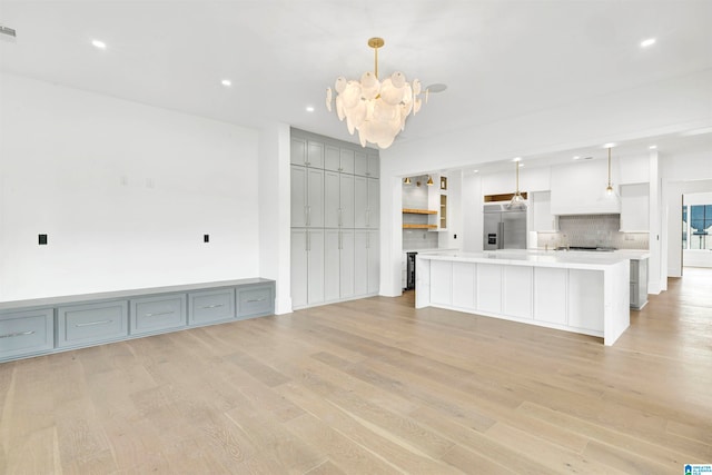 kitchen with hanging light fixtures, backsplash, an inviting chandelier, light hardwood / wood-style floors, and a kitchen island