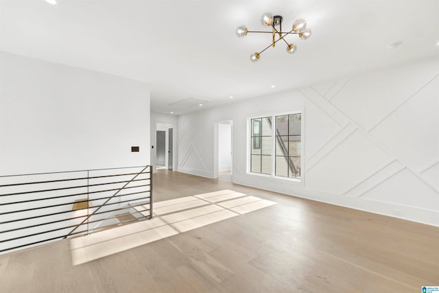 unfurnished room featuring an inviting chandelier and light hardwood / wood-style floors