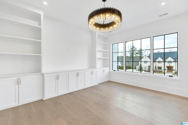 unfurnished room featuring light wood-type flooring and a notable chandelier