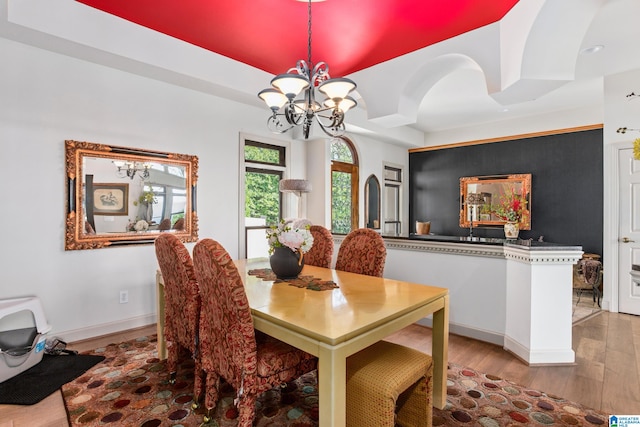 dining area with light hardwood / wood-style flooring and an inviting chandelier