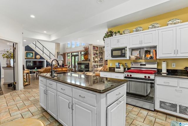 kitchen with dark stone counters, sink, a kitchen island, white cabinetry, and stainless steel range with gas stovetop