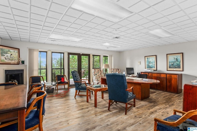 office area with french doors, light hardwood / wood-style flooring, and a drop ceiling