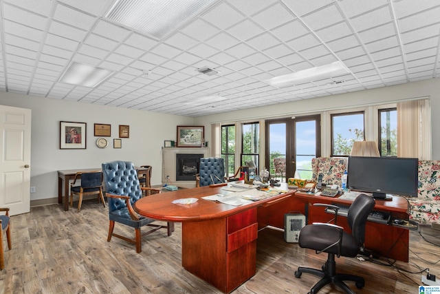 office space with hardwood / wood-style floors, a drop ceiling, and french doors