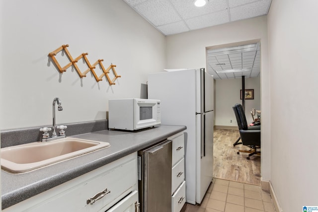 kitchen featuring sink, light tile patterned floors, stainless steel appliances, and a drop ceiling