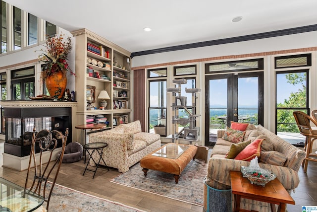 living area featuring a multi sided fireplace, french doors, hardwood / wood-style flooring, and ornamental molding