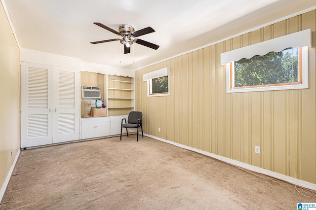 unfurnished bedroom featuring ceiling fan, light carpet, wooden walls, and a wall unit AC