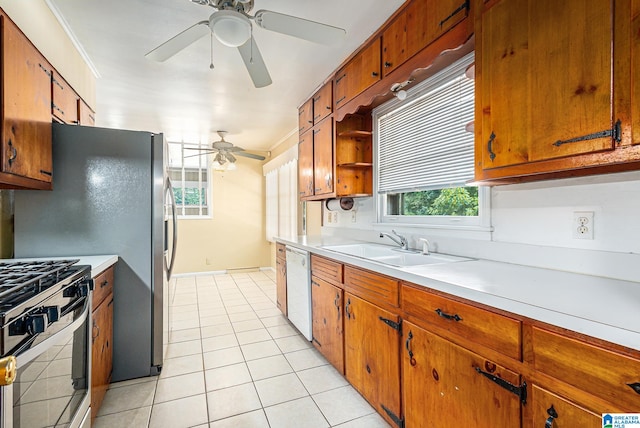 kitchen with stainless steel gas range oven, light tile patterned floors, dishwasher, sink, and ceiling fan