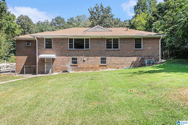 rear view of house with central AC and a lawn