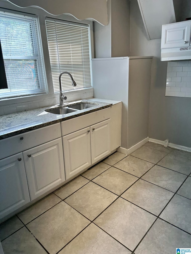 kitchen with light tile patterned floors, white cabinetry, and sink