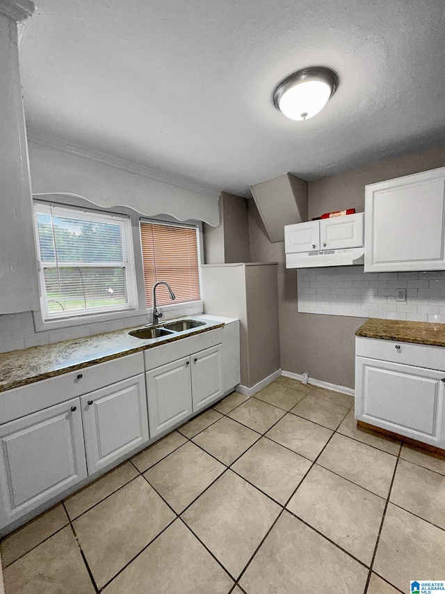 kitchen featuring light tile patterned floors, crown molding, white cabinetry, sink, and a textured ceiling