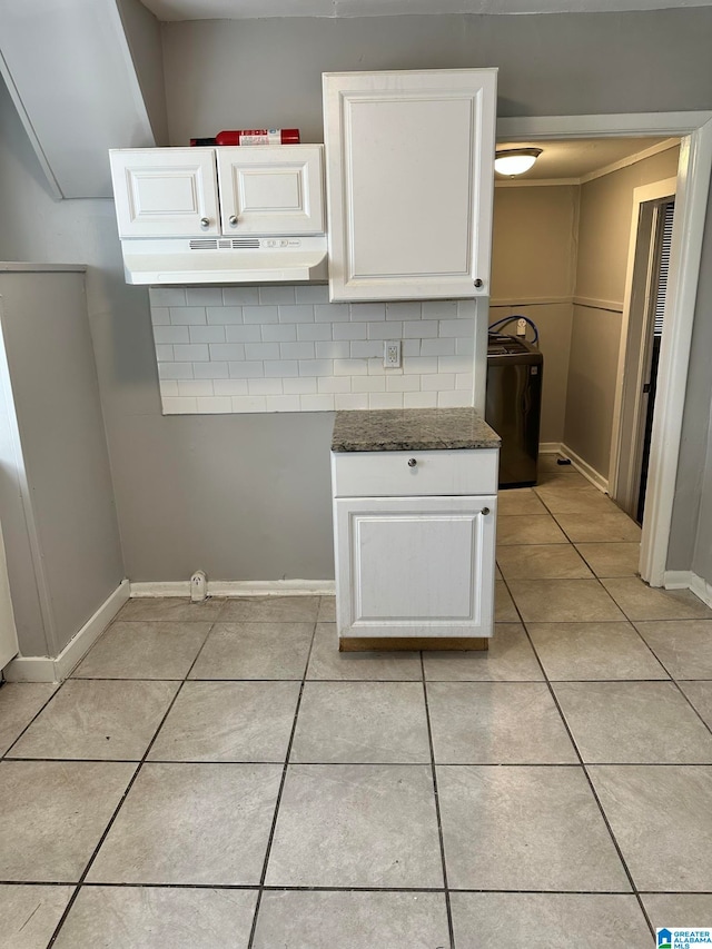 kitchen with washer / dryer, dark stone counters, white cabinetry, and backsplash