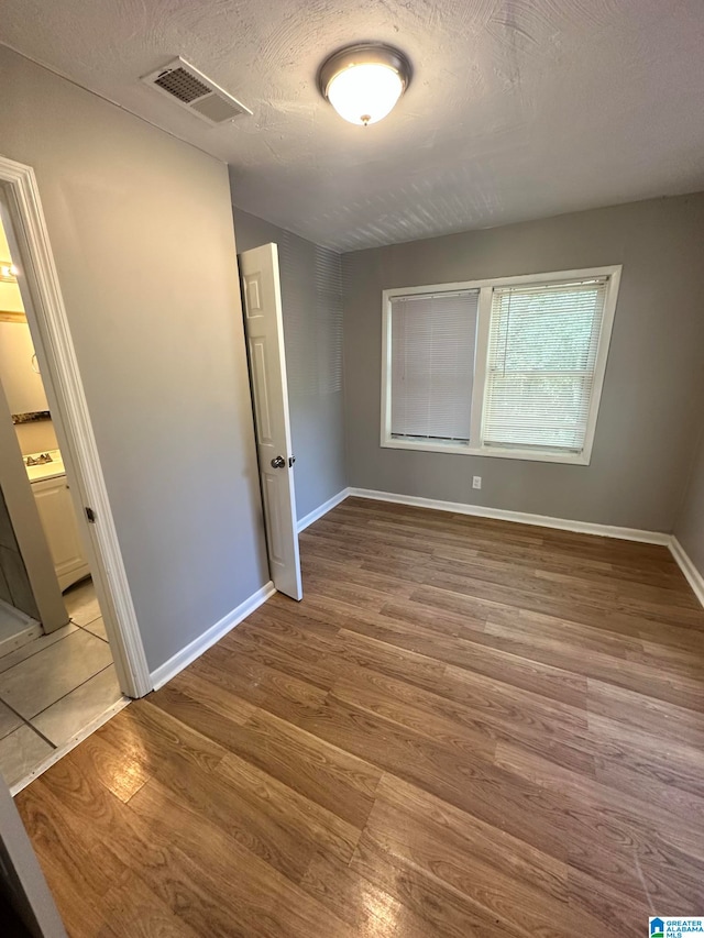 spare room with light hardwood / wood-style floors and a textured ceiling