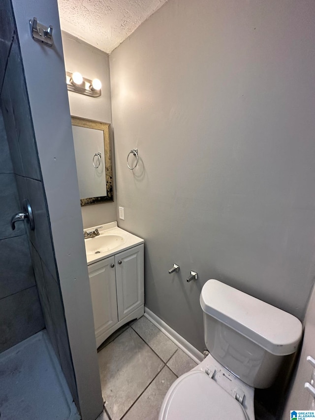 bathroom with a textured ceiling, vanity, toilet, tile patterned floors, and a shower