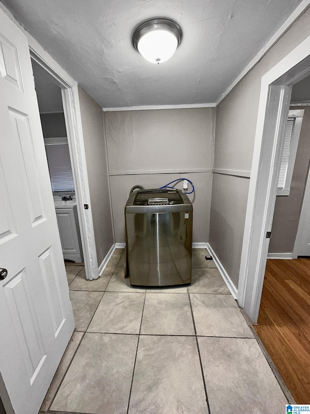 clothes washing area featuring a textured ceiling, light hardwood / wood-style flooring, and washer / clothes dryer