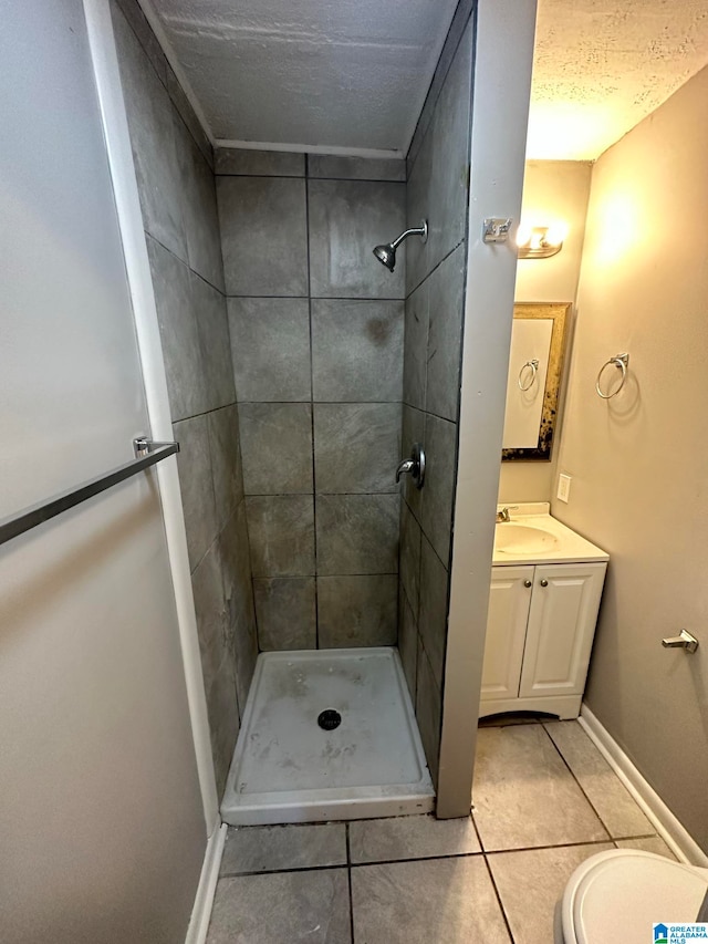 bathroom with vanity, a textured ceiling, tiled shower, and tile patterned floors