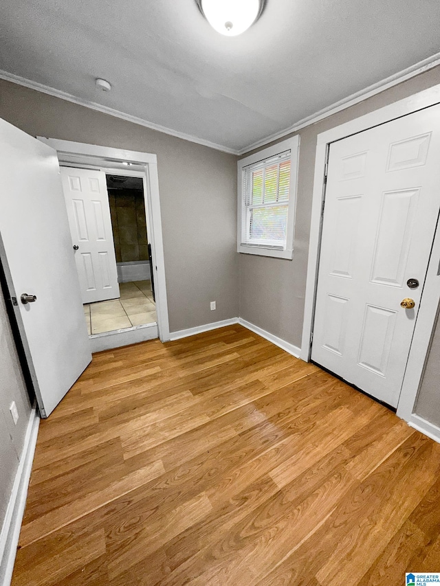 unfurnished bedroom featuring ornamental molding and light hardwood / wood-style flooring